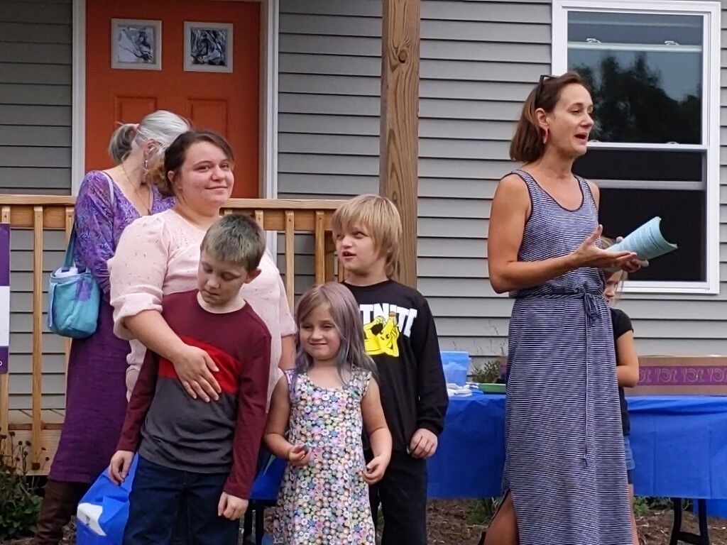 Tamrie Oliver stands with her three children while Liz Warner talks at the celebration for the completion of the house.